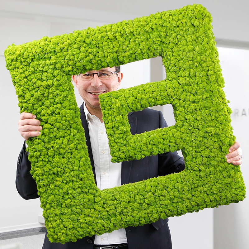 Hakan Baran Geschäftsführer ECON Application GmbH hält das Logo von ECON